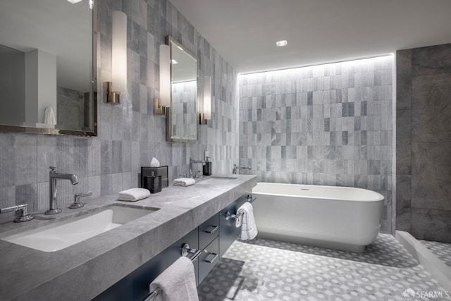 bathroom with vanity, tile walls, and a tub