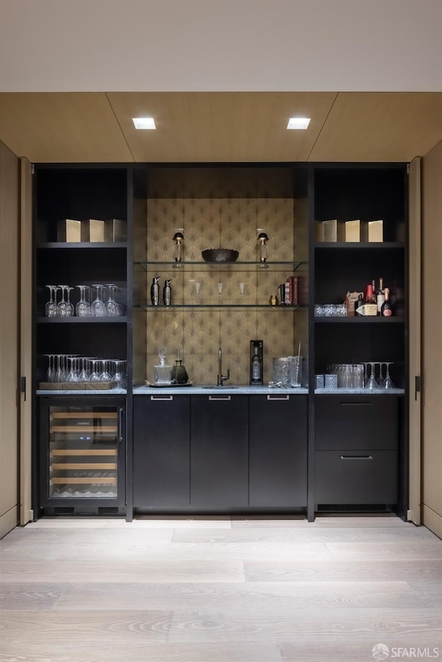 bar featuring sink, built in features, beverage cooler, and light hardwood / wood-style flooring