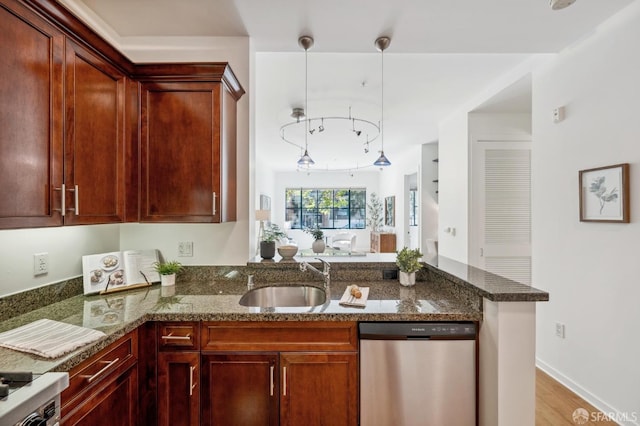 kitchen featuring dark stone counters, a sink, a peninsula, and stainless steel dishwasher