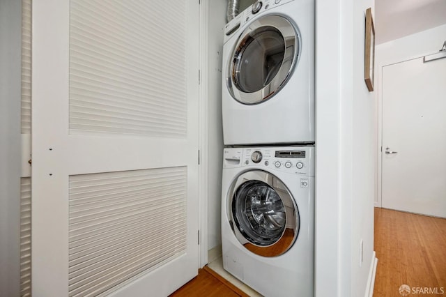 washroom with laundry area, stacked washing maching and dryer, and wood finished floors