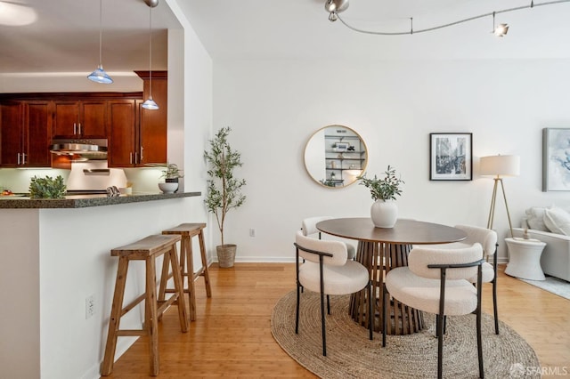 dining area with light wood-type flooring and baseboards