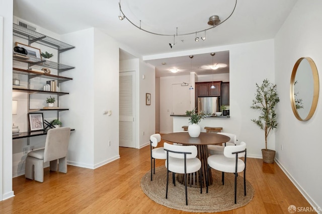 dining room with baseboards, rail lighting, visible vents, and light wood-style floors