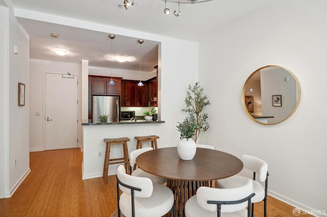 dining space with light wood finished floors and baseboards