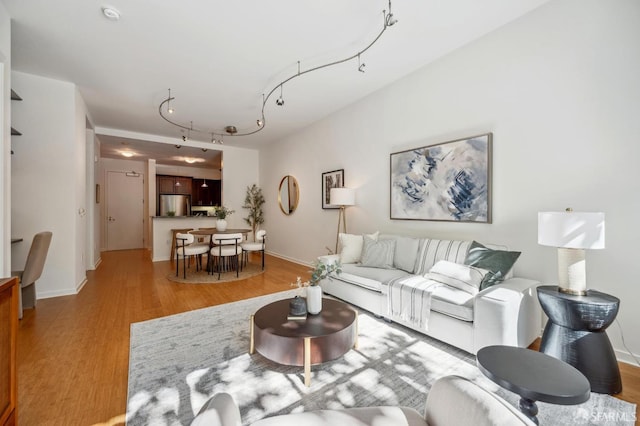 living area with rail lighting, baseboards, and wood finished floors