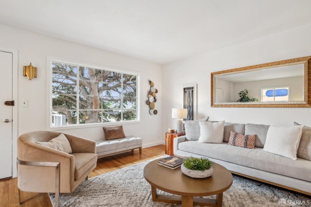 living area with baseboards, a healthy amount of sunlight, and wood finished floors
