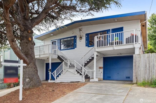 view of front facade featuring concrete driveway, fence, stairs, and a garage