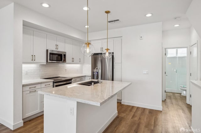 3821 Wattling St, Oakland, CA 94601 - kitchen with stainless steel appliances, a sink, white cabinets, wood finished floors, and decorative backsplash