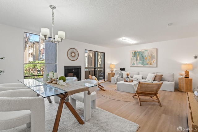 dining area featuring an inviting chandelier, a textured ceiling, and light hardwood / wood-style floors