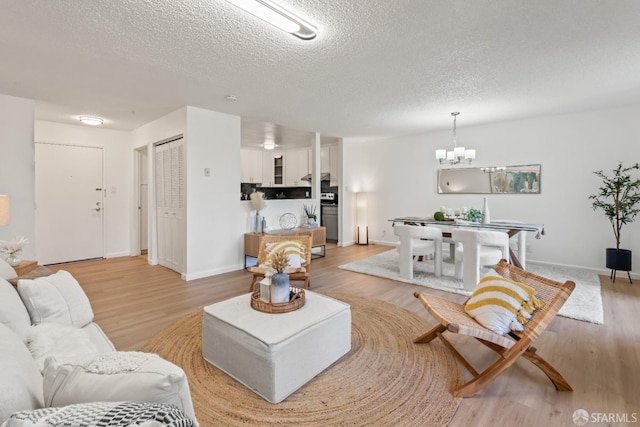 living room with a textured ceiling, a chandelier, and light hardwood / wood-style flooring