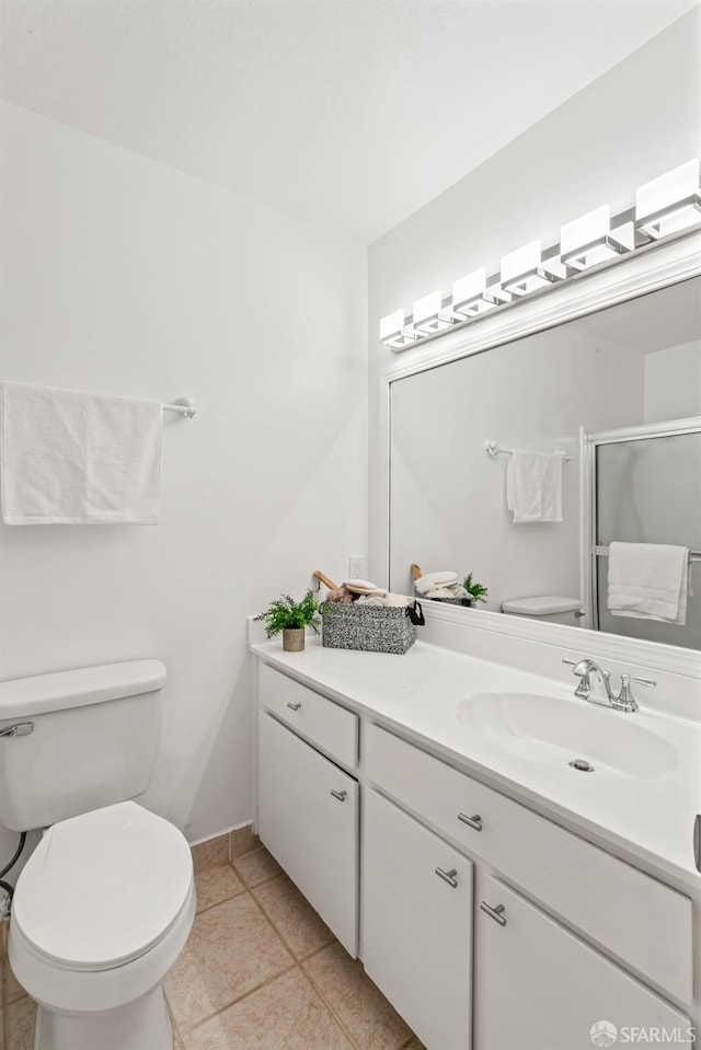 bathroom with a shower with shower door, vanity, tile patterned floors, and toilet