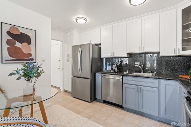 kitchen with appliances with stainless steel finishes, white cabinetry, sink, backsplash, and light tile patterned floors