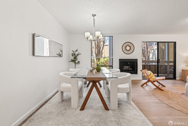 dining space with hardwood / wood-style flooring, a textured ceiling, and an inviting chandelier