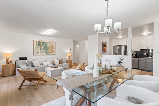 dining space featuring sink, a textured ceiling, light hardwood / wood-style flooring, and a chandelier