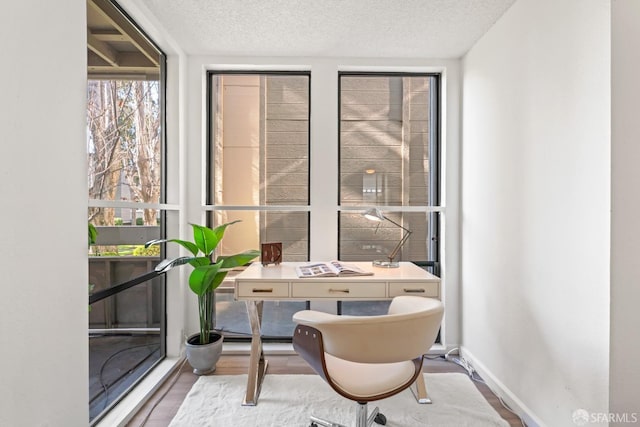 interior space with a textured ceiling, a wall of windows, and hardwood / wood-style floors