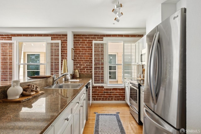 323 29th St Unit C301, San Francisco, CA 94131 - kitchen with stainless steel appliances, light wood finished floors, brick wall, white cabinets, and dark stone countertops