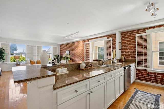 323 29th St Unit C301, San Francisco, CA 94131 - kitchen with brick wall, stainless steel dishwasher, light wood-type flooring, white cabinets, and dark stone countertops