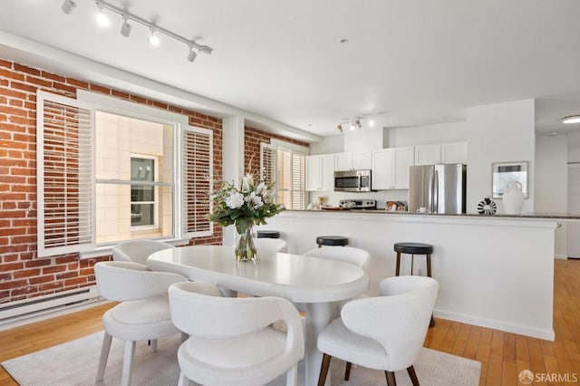 323 29th St Unit C301, San Francisco, CA 94131 - dining room with light wood-style flooring, baseboard heating, rail lighting, and brick wall