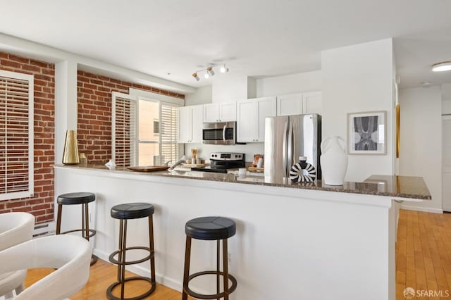 323 29th St Unit C301, San Francisco, CA 94131 - kitchen featuring stainless steel appliances, a breakfast bar, dark stone counters, and light wood-style floors