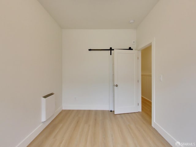 spare room featuring a barn door and light wood-type flooring