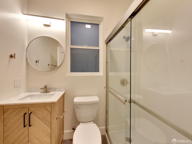 bathroom featuring toilet, vanity, and a shower with shower door