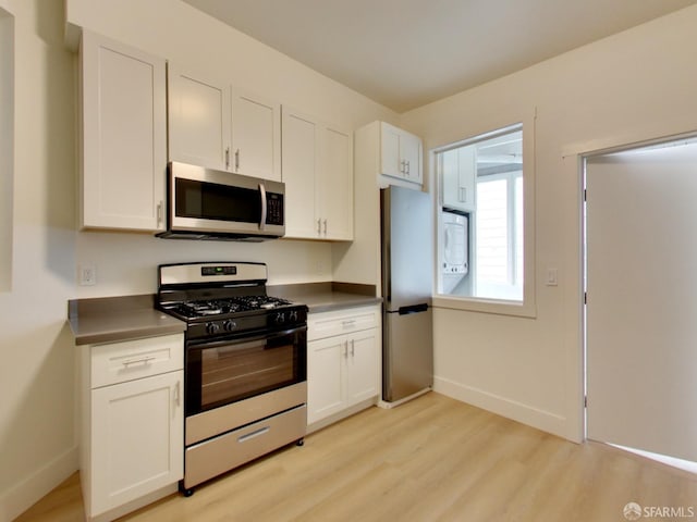 kitchen with stainless steel appliances, white cabinets, and light wood-type flooring