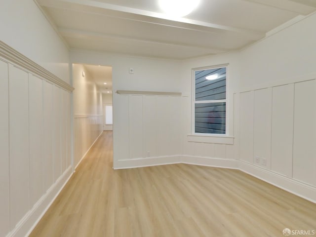 unfurnished room featuring beamed ceiling and light hardwood / wood-style floors