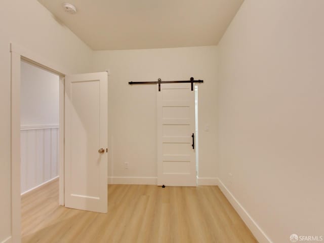 spare room featuring light hardwood / wood-style floors and a barn door