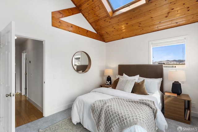 bedroom featuring wooden ceiling, vaulted ceiling with skylight, baseboards, and carpet floors