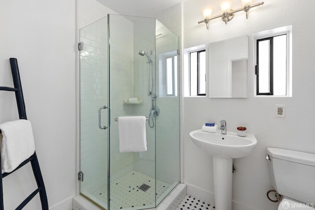 full bathroom with a shower stall, toilet, baseboards, and a sink