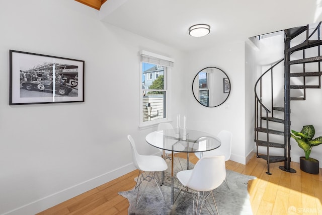 dining room featuring baseboards, wood finished floors, and stairs