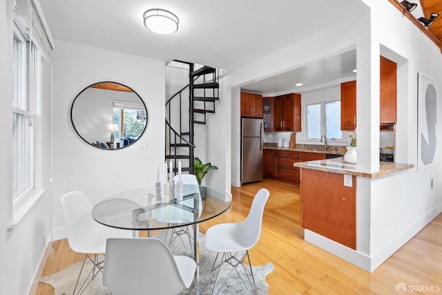 dining area featuring stairway, baseboards, and light wood-type flooring