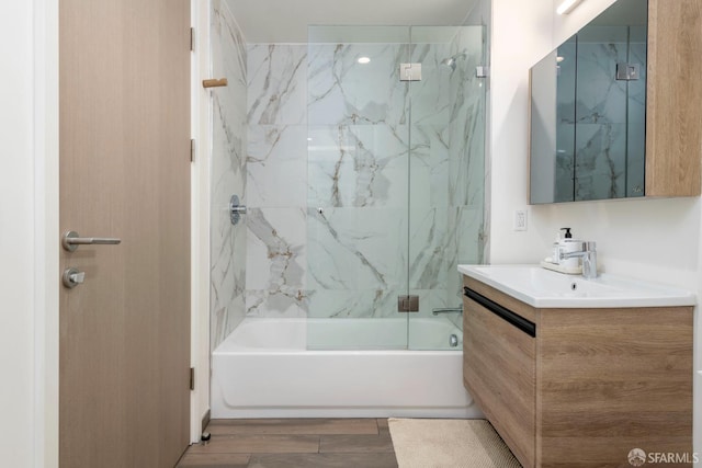 bathroom with wood-type flooring, tiled shower / bath, and vanity