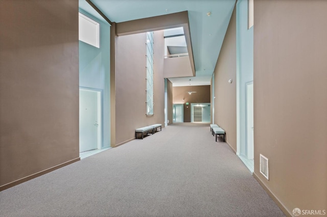 hall featuring a towering ceiling and carpet flooring