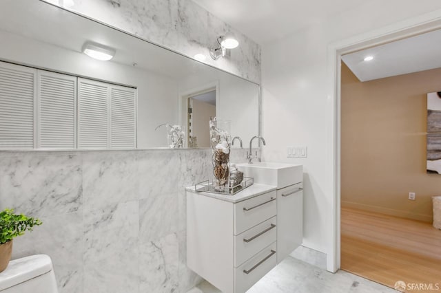 bathroom with toilet, vanity, and tile walls