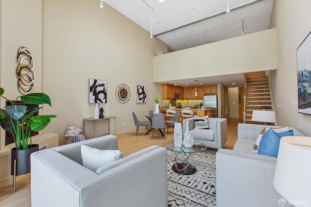 living room with a high ceiling, light hardwood / wood-style floors, and a skylight