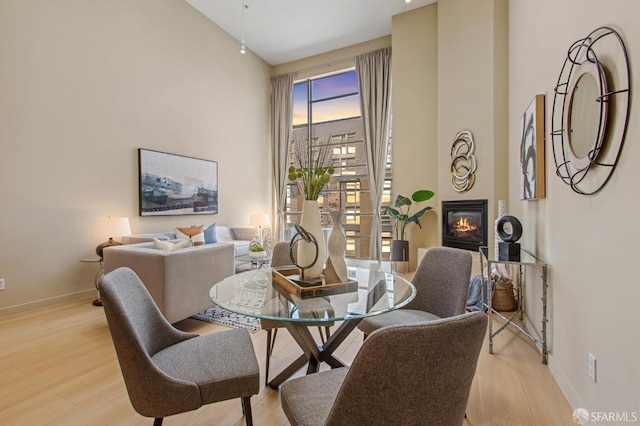 dining area featuring high vaulted ceiling and light wood-type flooring