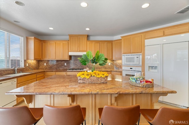 kitchen featuring built in appliances, a kitchen island, a breakfast bar area, and sink