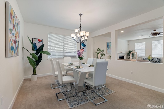 carpeted dining area with ceiling fan with notable chandelier