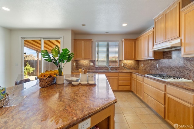 kitchen with tasteful backsplash, white gas cooktop, light tile patterned floors, sink, and light brown cabinets