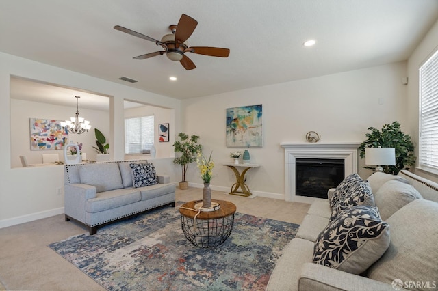 carpeted living room with ceiling fan with notable chandelier