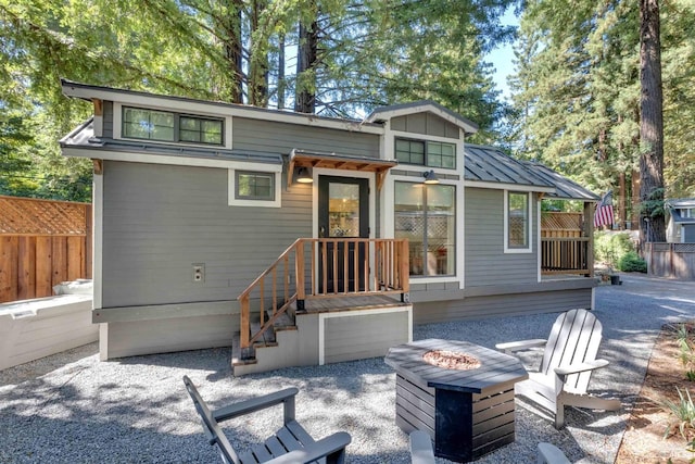 rear view of property featuring a patio, a fire pit, fence, board and batten siding, and a standing seam roof