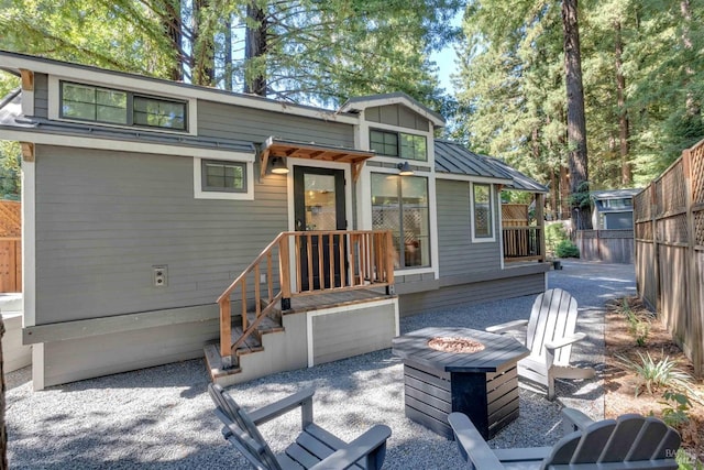 back of house featuring a fire pit, a patio, metal roof, a standing seam roof, and fence