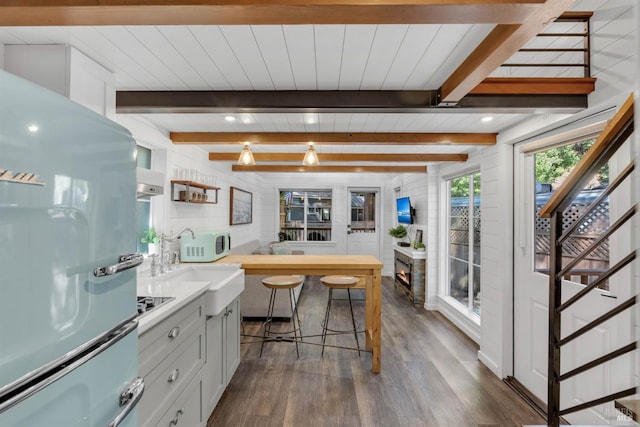 kitchen featuring white appliances, dark wood finished floors, beam ceiling, light countertops, and a sink