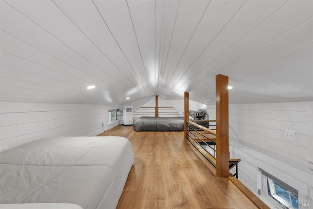 bedroom with wood walls, vaulted ceiling, and wood finished floors