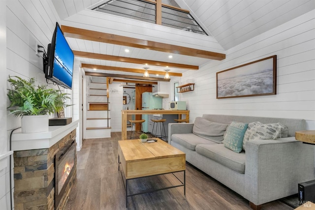 living area with lofted ceiling with beams, a fireplace, wood finished floors, and wooden walls