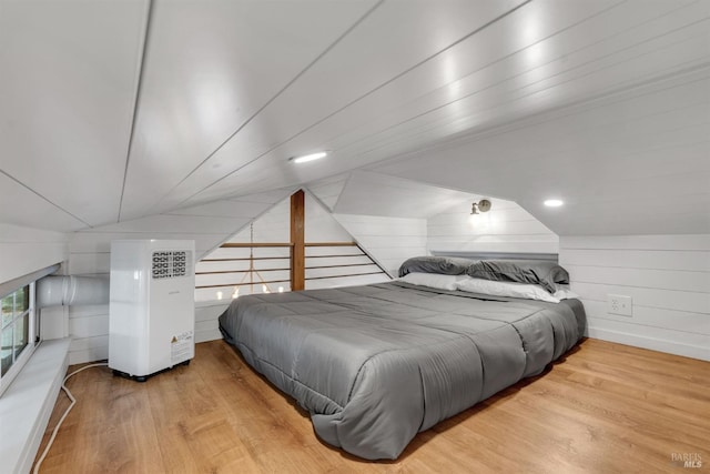 bedroom featuring vaulted ceiling, wood walls, and wood finished floors