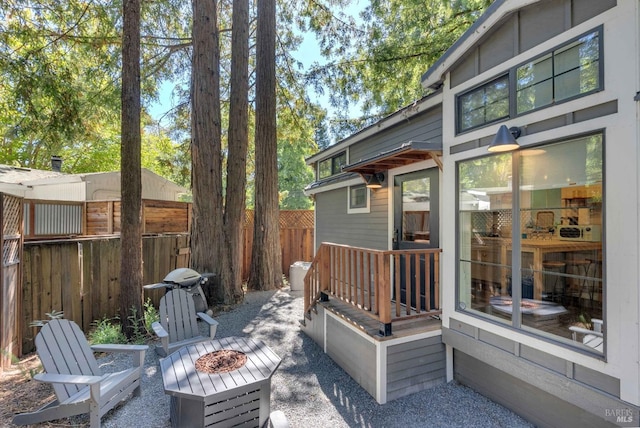 wooden deck with an outdoor fire pit, fence, and grilling area