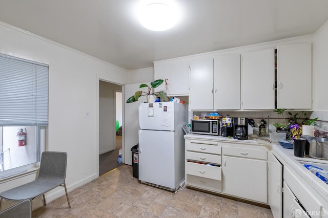 kitchen featuring white cabinets, crown molding, and white fridge