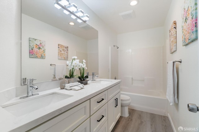 full bath with toilet, visible vents, a sink, and wood finished floors