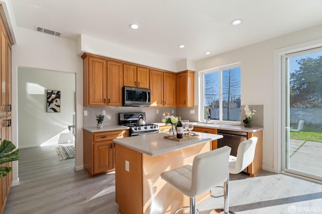 kitchen with stainless steel appliances, a kitchen island, visible vents, a wealth of natural light, and tasteful backsplash